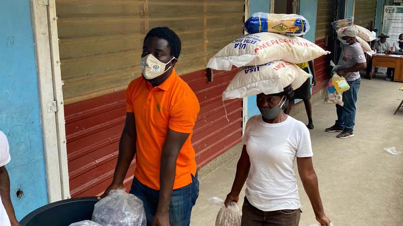 a man and a woman carrying food donated to them by ADRA canada.